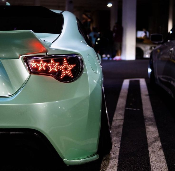 two cars parked next to each other in a parking lot at night with lights on them