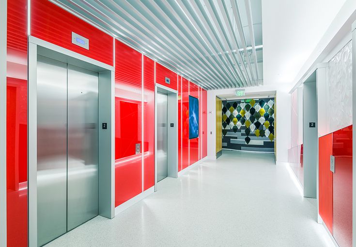 an empty hallway with red and silver doors