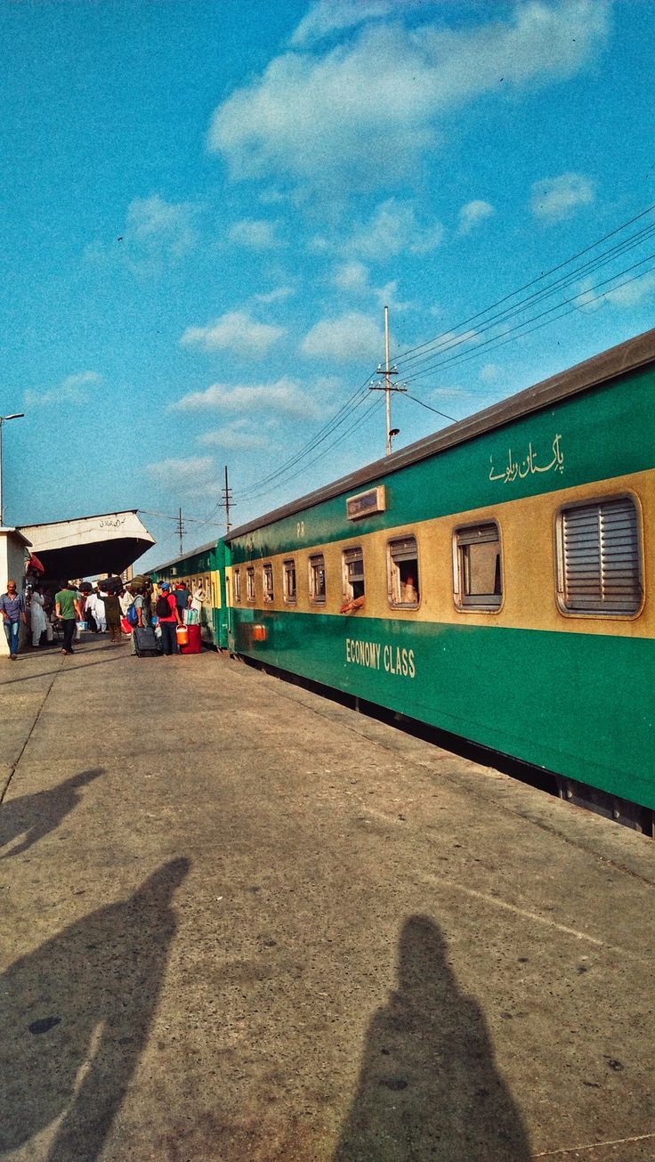 people standing next to a green and yellow train