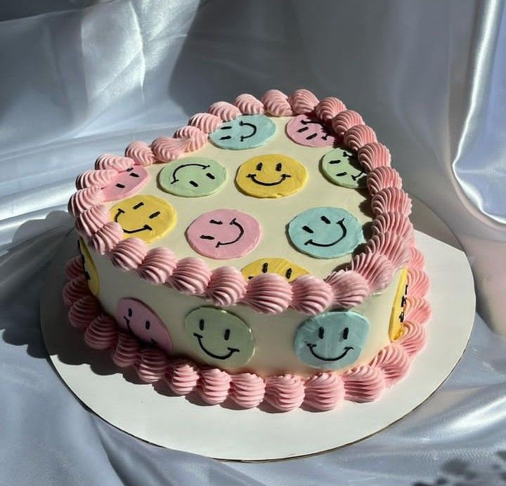 a cake with smiley faces on it sitting on top of a white tableclothed cloth