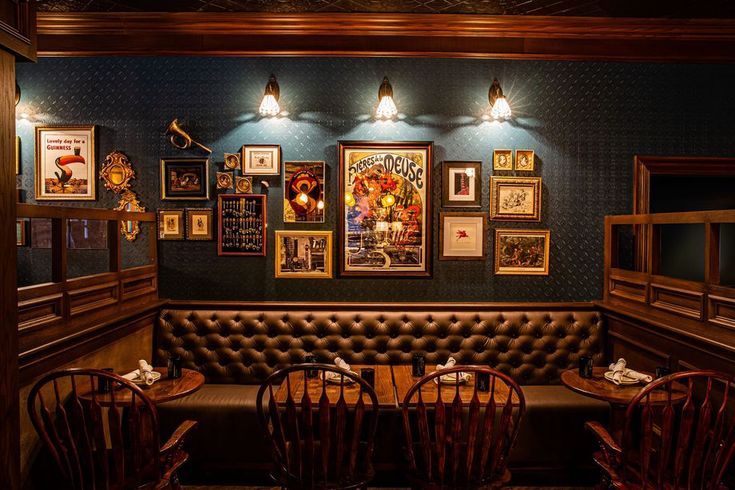 a restaurant with wooden tables and chairs in front of a blue wall filled with framed pictures