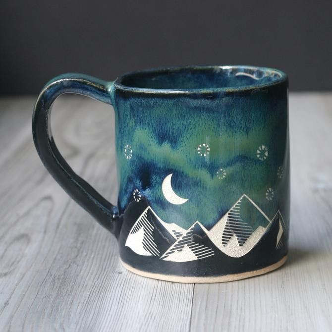 a ceramic mug with mountains and stars painted on it