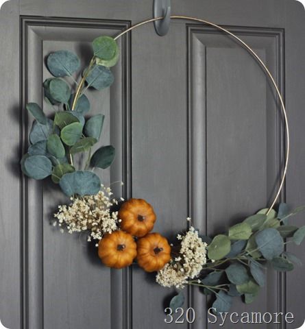 a wreath with pumpkins and greenery hangs on a door