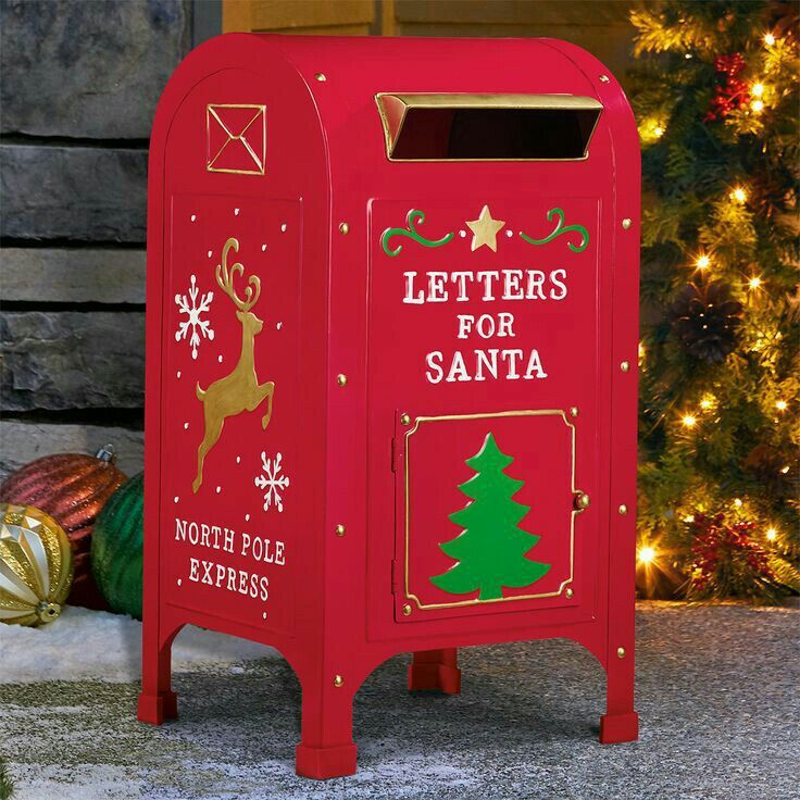 a red mailbox sitting in front of a christmas tree with letters for santa written on it