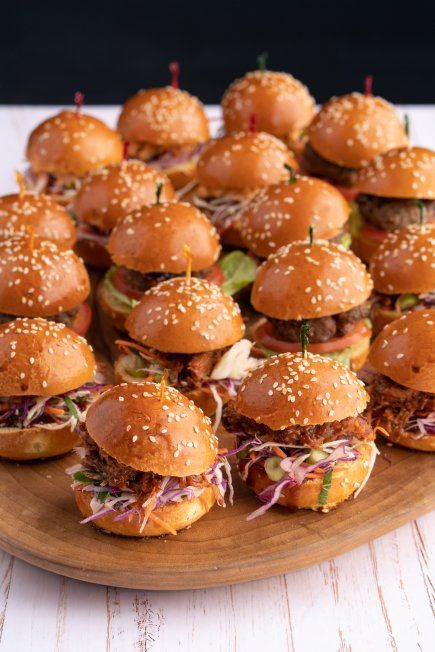 a wooden platter filled with mini hamburgers