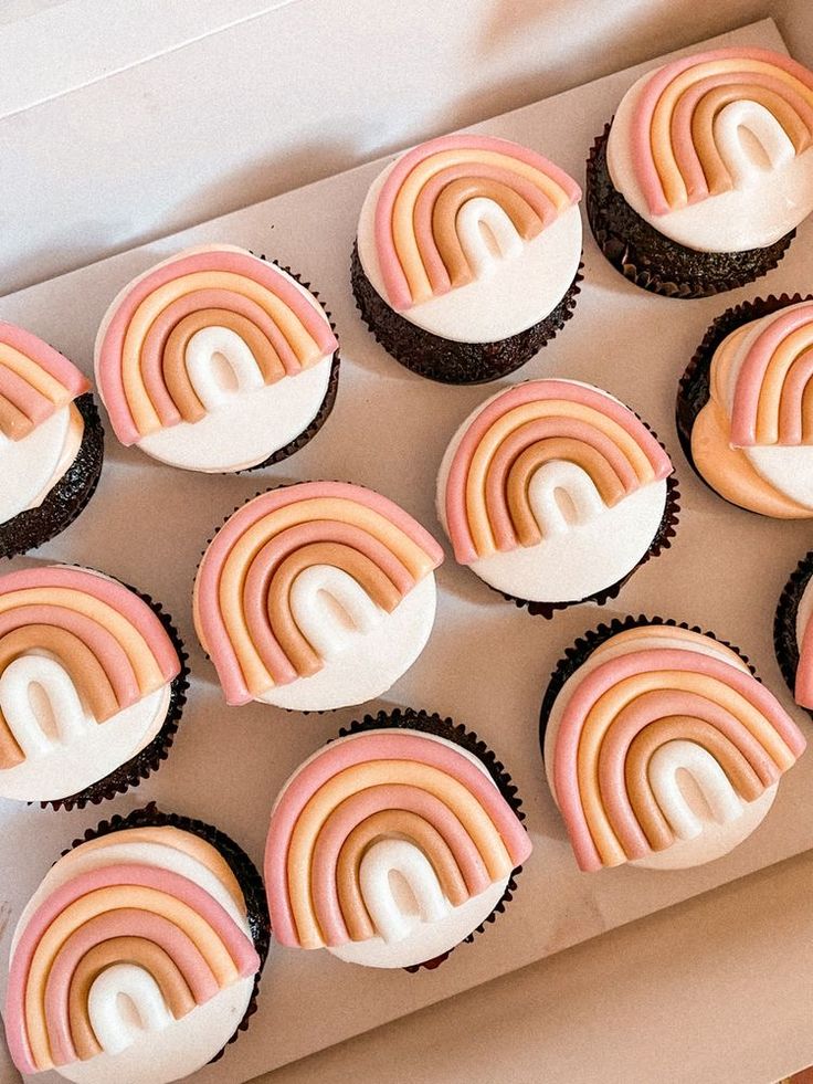 cupcakes with pink and white frosting are arranged in a box on the table