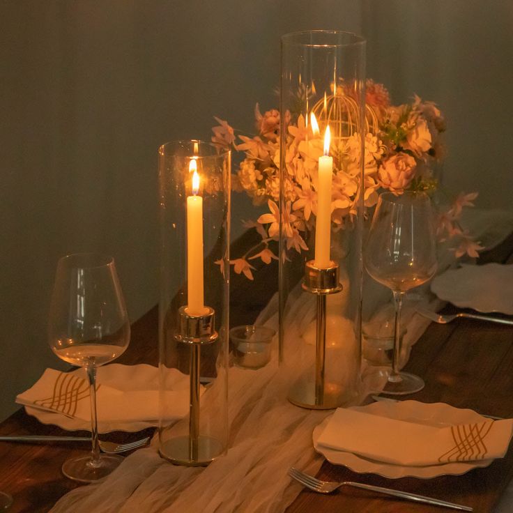 the table is set with candles, napkins and wine glasses for an elegant dinner