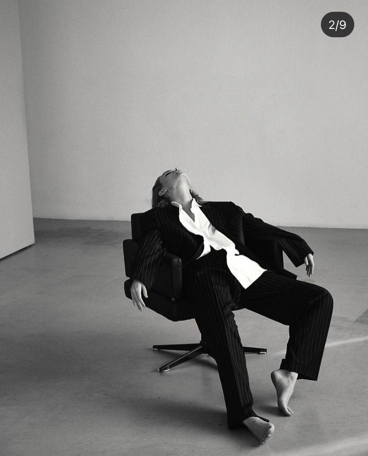 a man in a suit and tie sitting on a chair with his feet up to the ground