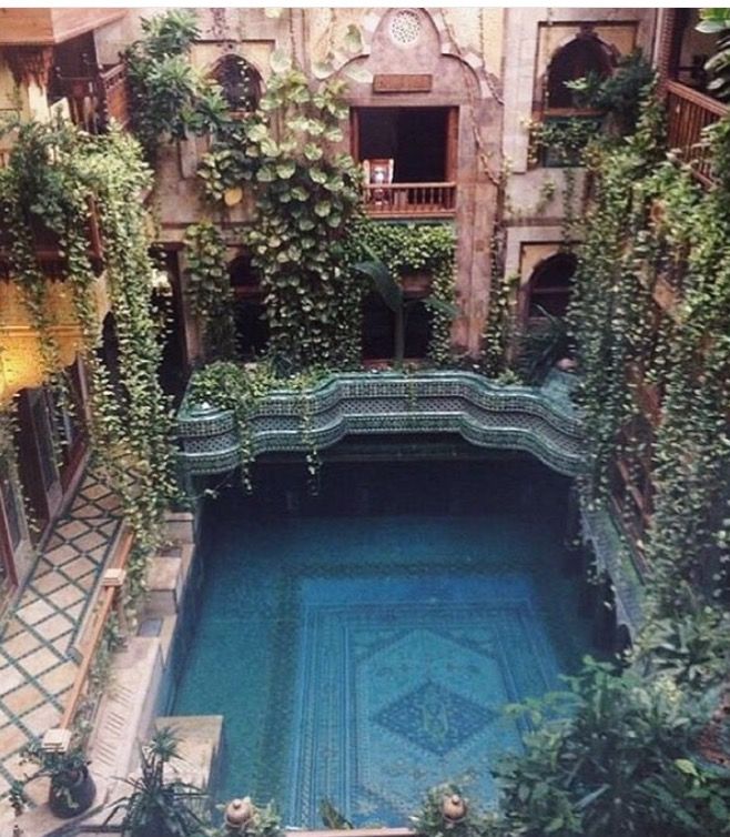 an indoor swimming pool surrounded by greenery in a building with two balconies