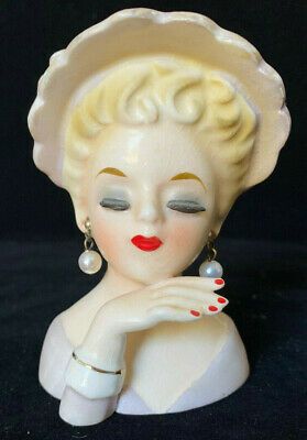 a white ceramic figurine wearing a hat and pearls