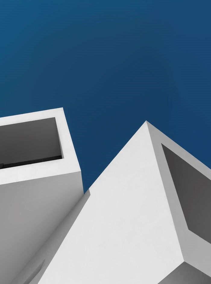 the corner of a white building with a blue sky in the backgrounnd