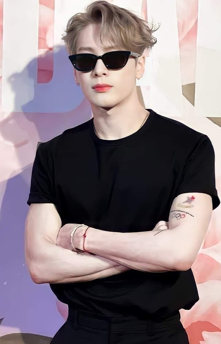 a man with his arms crossed wearing sunglasses