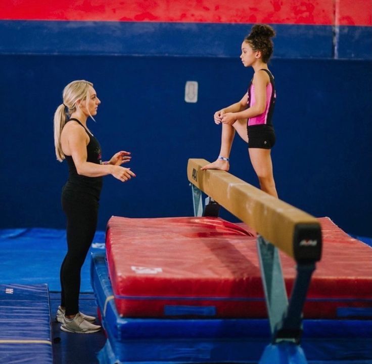 two girls are standing on the balance bars