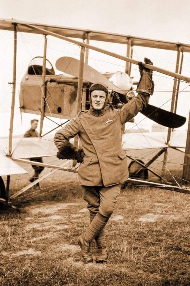 an old photo of a man standing in front of a plane with his hands up