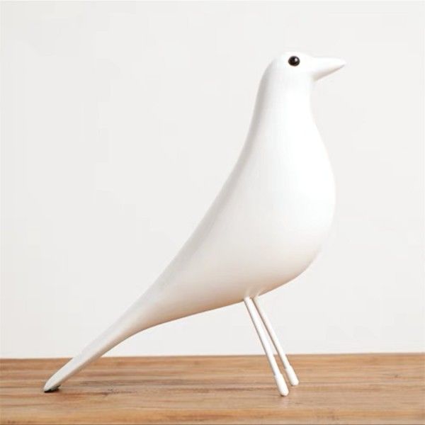 a white bird statue sitting on top of a wooden table