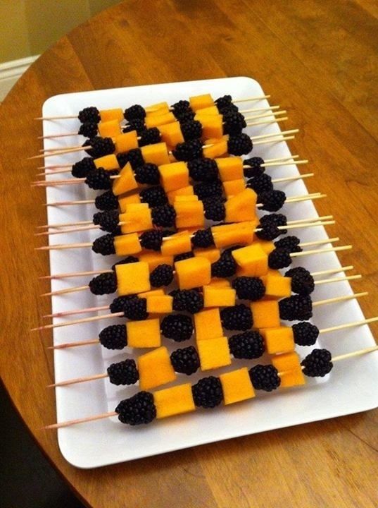 some food is on a white plate and has blackberries and orange for halloween fun