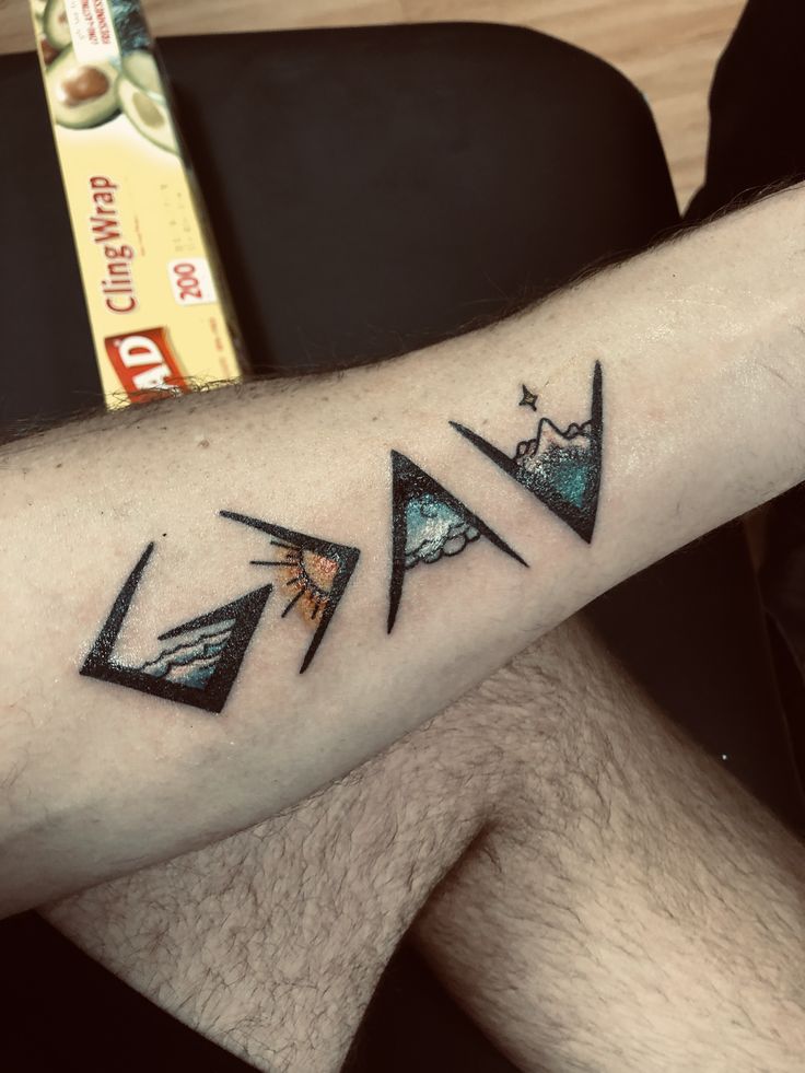 a man's arm with three triangle tattoos on it