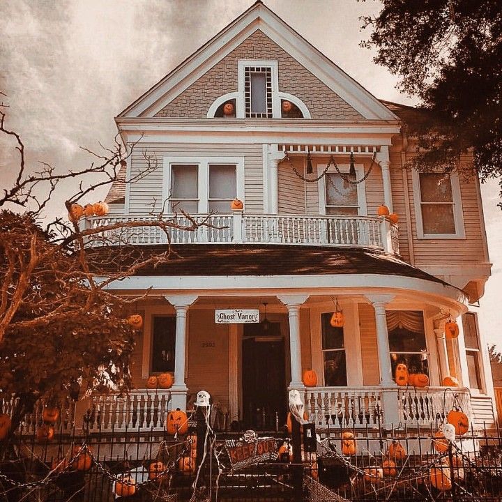 a house decorated for halloween with pumpkins on the porch