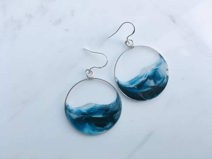 a pair of blue and white earrings sitting on top of a marble countertop next to each other