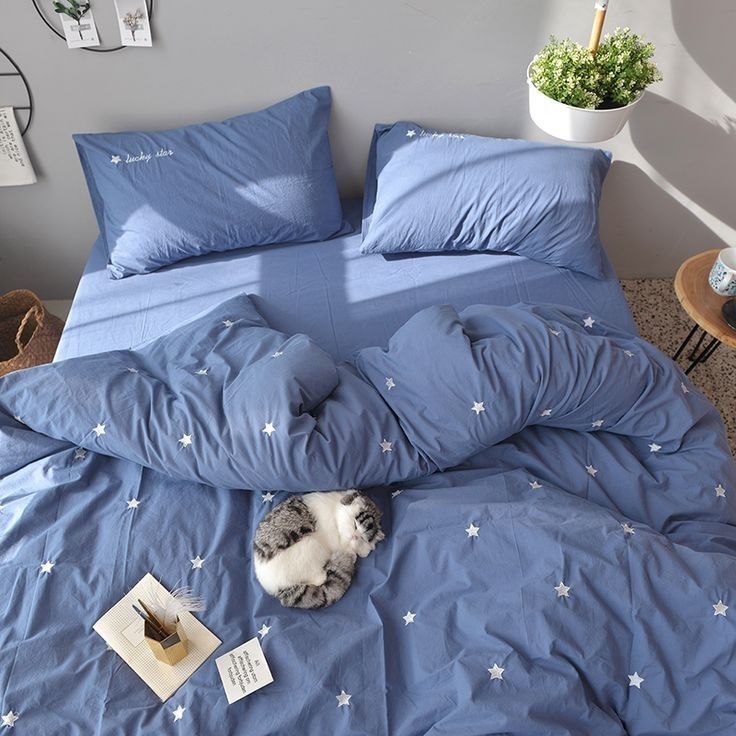 a cat laying on top of a blue comforter in a bed with white stars