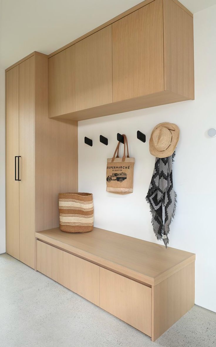 a wooden bench sitting next to a white wall with a hat on it's head