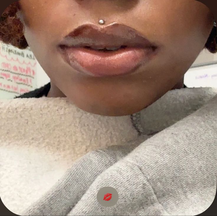 a close up of a person with a nose piercing on their lip and wearing a sweater