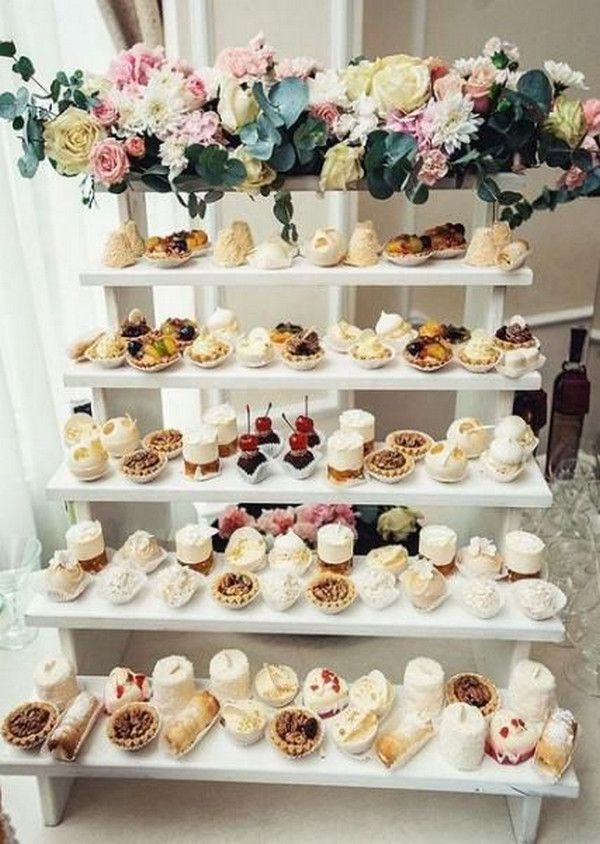 a white shelf filled with lots of different types of cakes and cupcakes on top of it