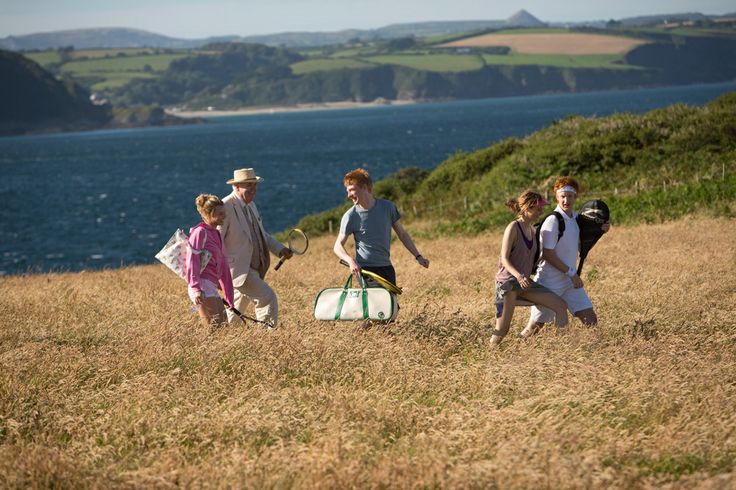 four people walking in the grass with luggage