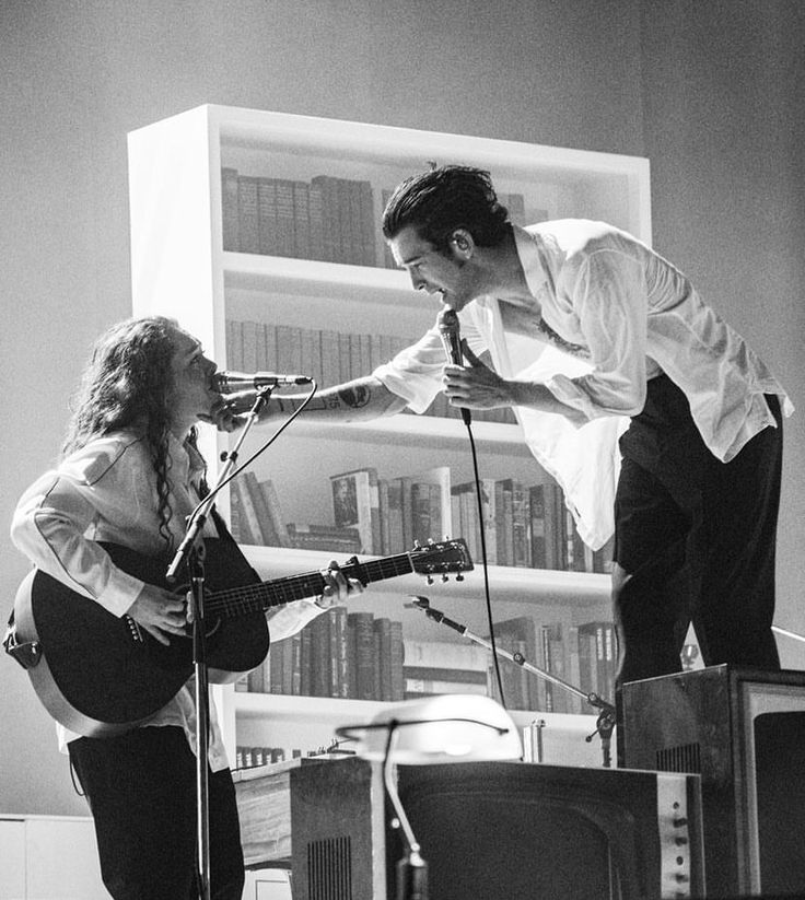 a man and woman playing instruments in front of a tv