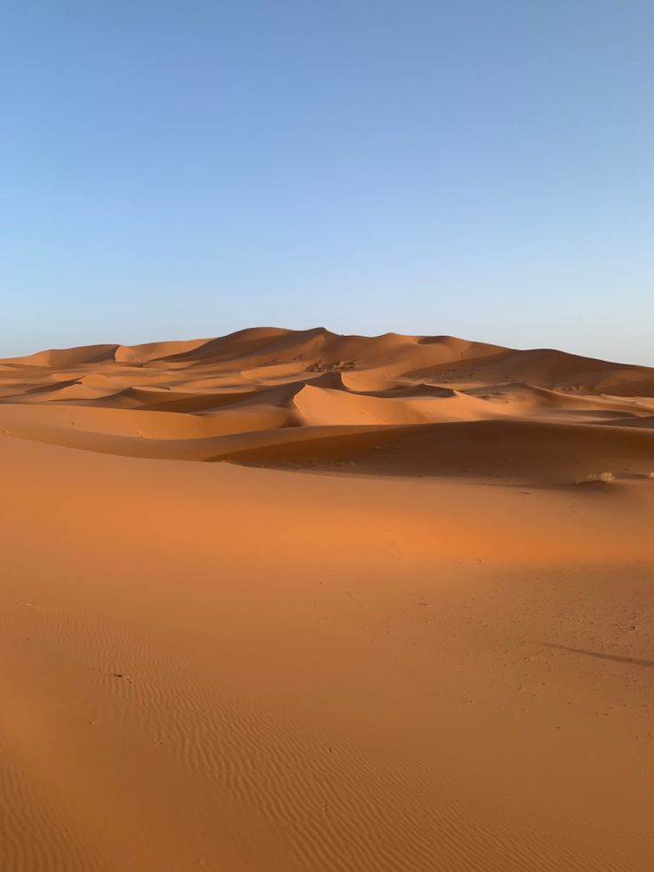 an empty desert with sand dunes in the distance