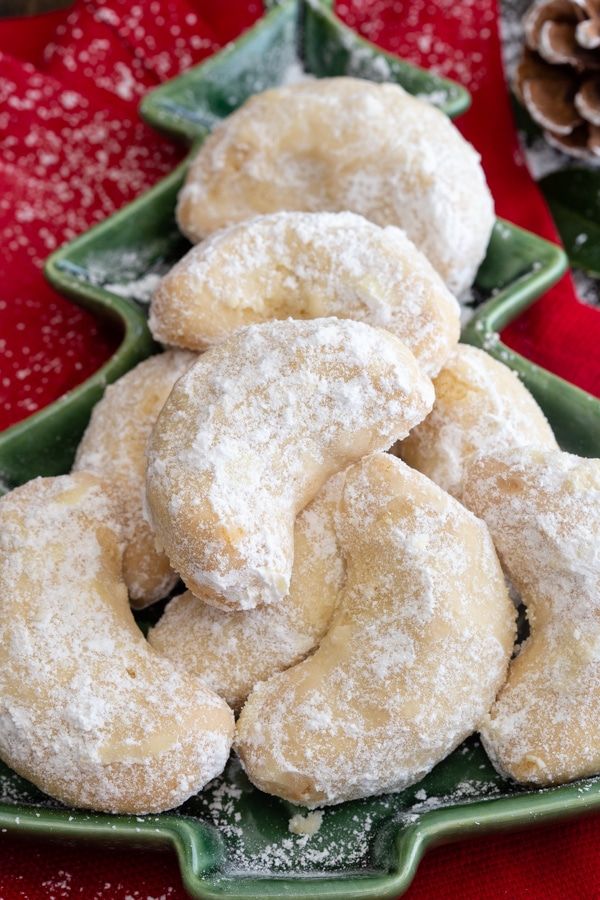 powdered sugar donuts stacked on top of each other in a green platter