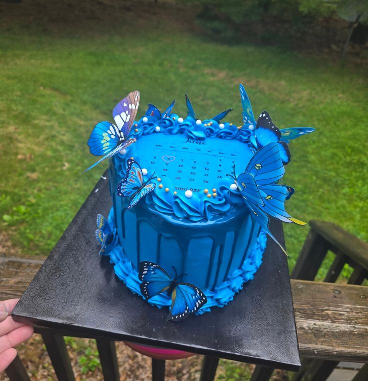 a blue cake sitting on top of a wooden table next to a green grass covered field