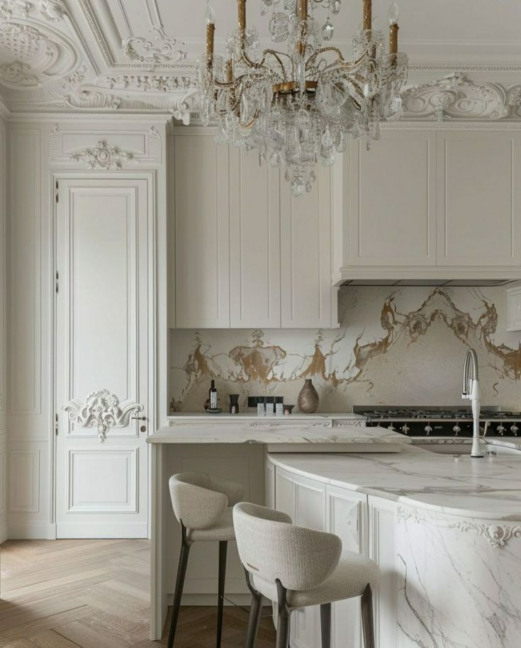 an elegant kitchen with marble counter tops and white cabinets, chandelier above the island