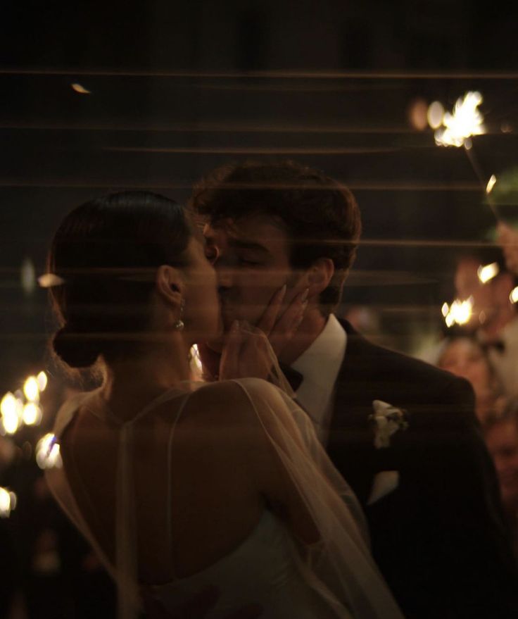 a bride and groom kissing in front of sparklers