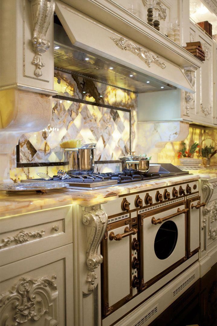 a kitchen with white cabinets and gold trimmings on the stove top, along with an oven