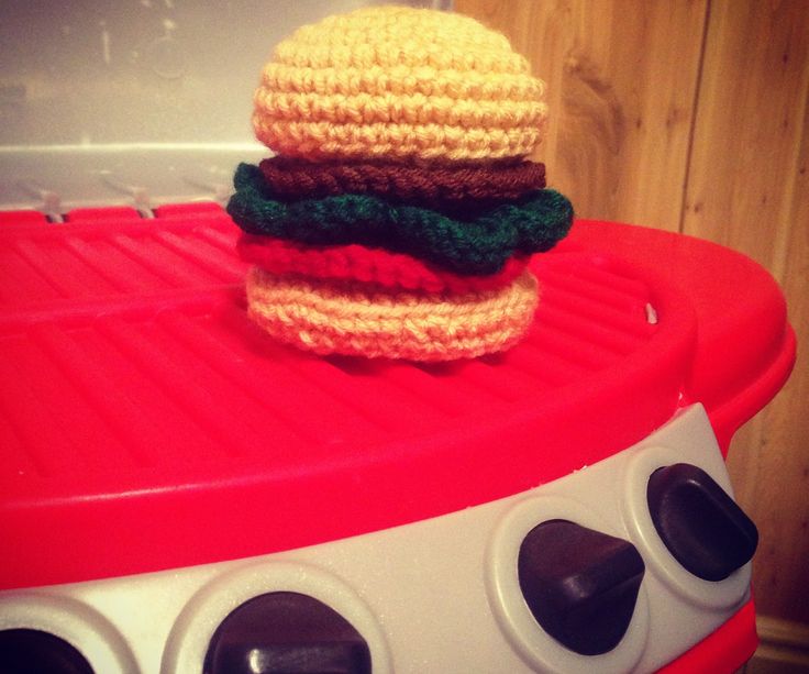 a crocheted hamburger sitting on top of a red grill