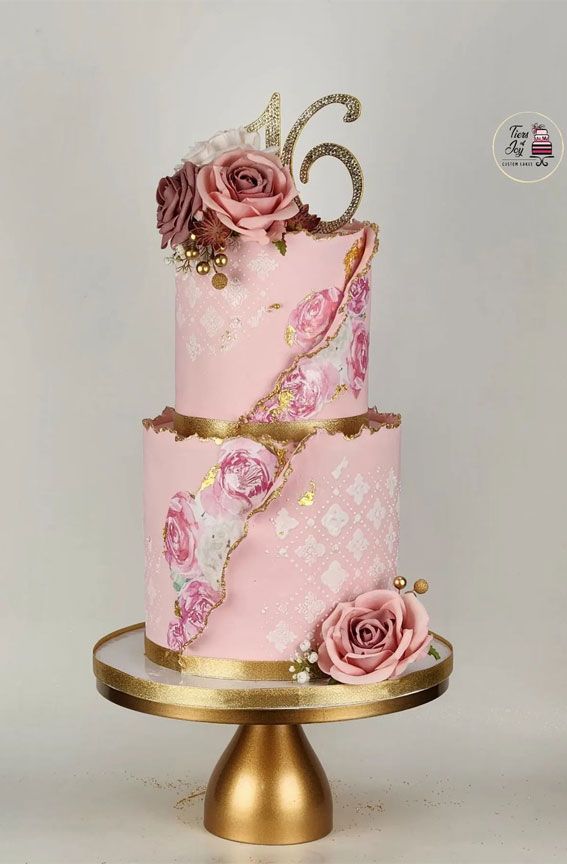 a pink and gold cake with roses on top