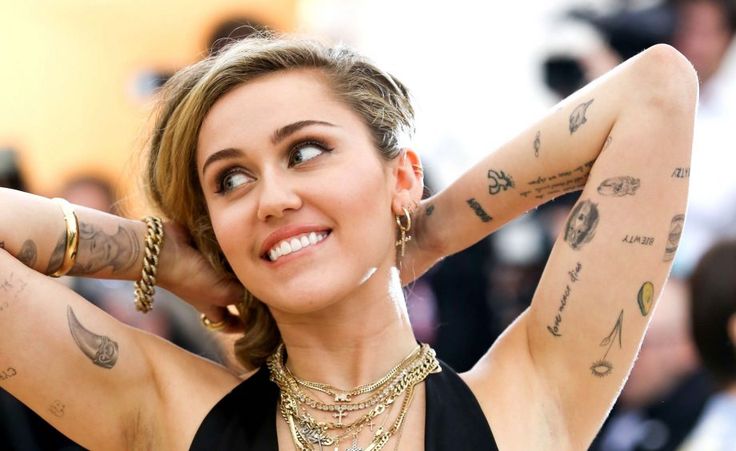 a woman with many tattoos on her arms and chest poses for the camera while holding her hands behind her head