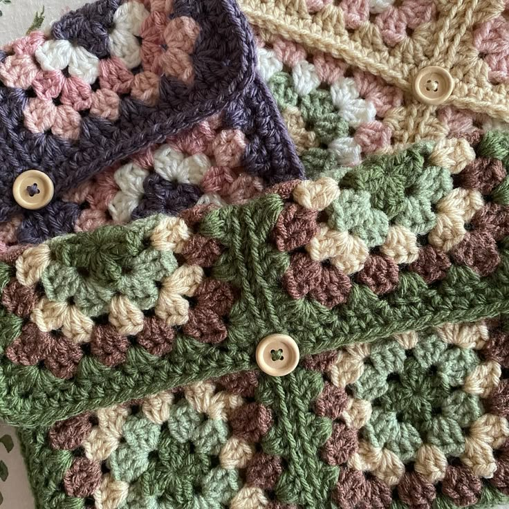 three crocheted granny afghans with buttons on them