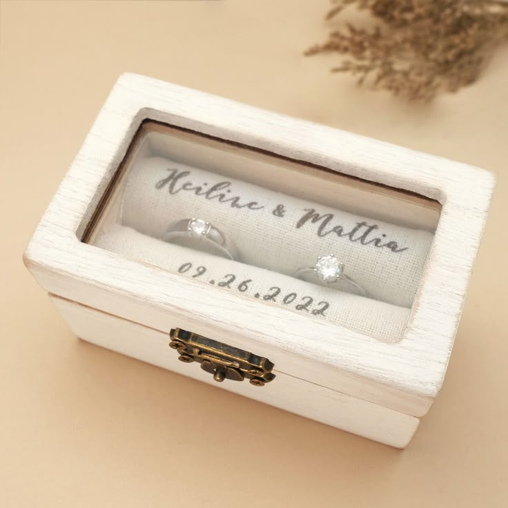 two wedding rings in a white box on a table