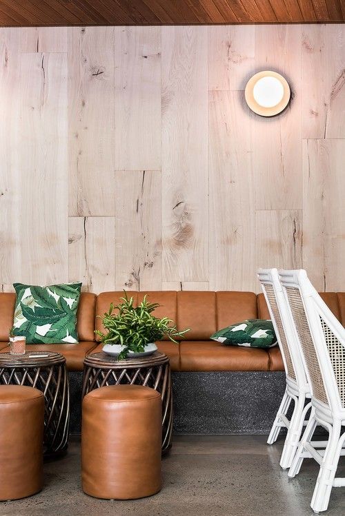 a living room filled with lots of furniture next to a wooden wall covered in wood planks