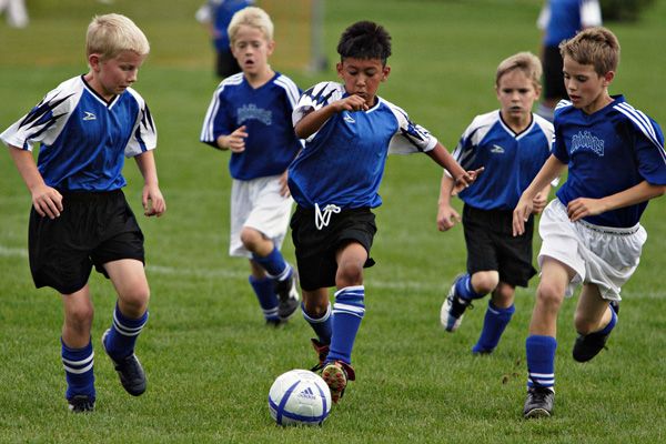 young boys playing soccer on a field with the words click here for soccer registration below