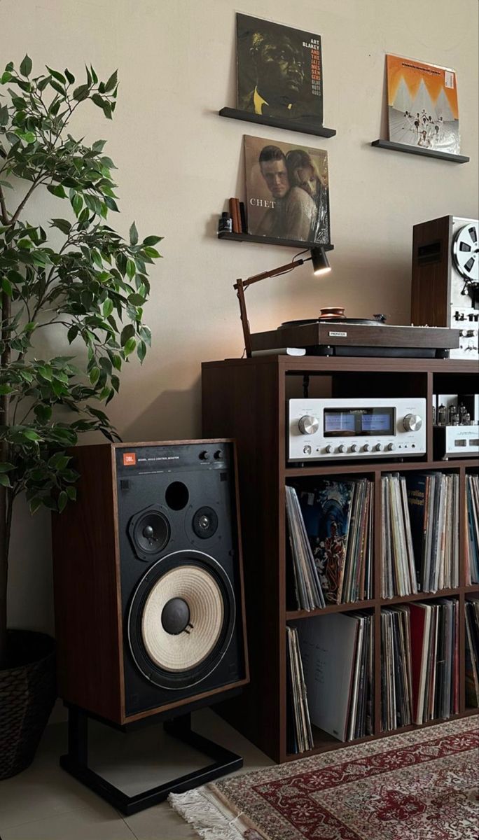 there is a record player and stereo in the corner next to a tree with records on it