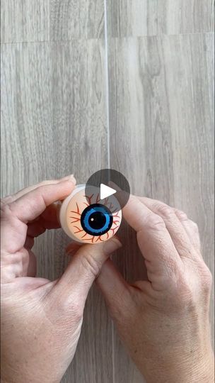 someone holding an eyeball in their hands on a wooden floor with wood planks