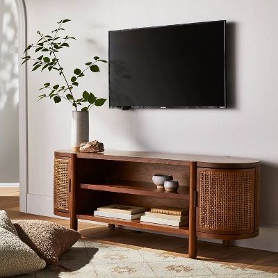 a flat screen tv mounted to the side of a wooden entertainment center next to a potted plant