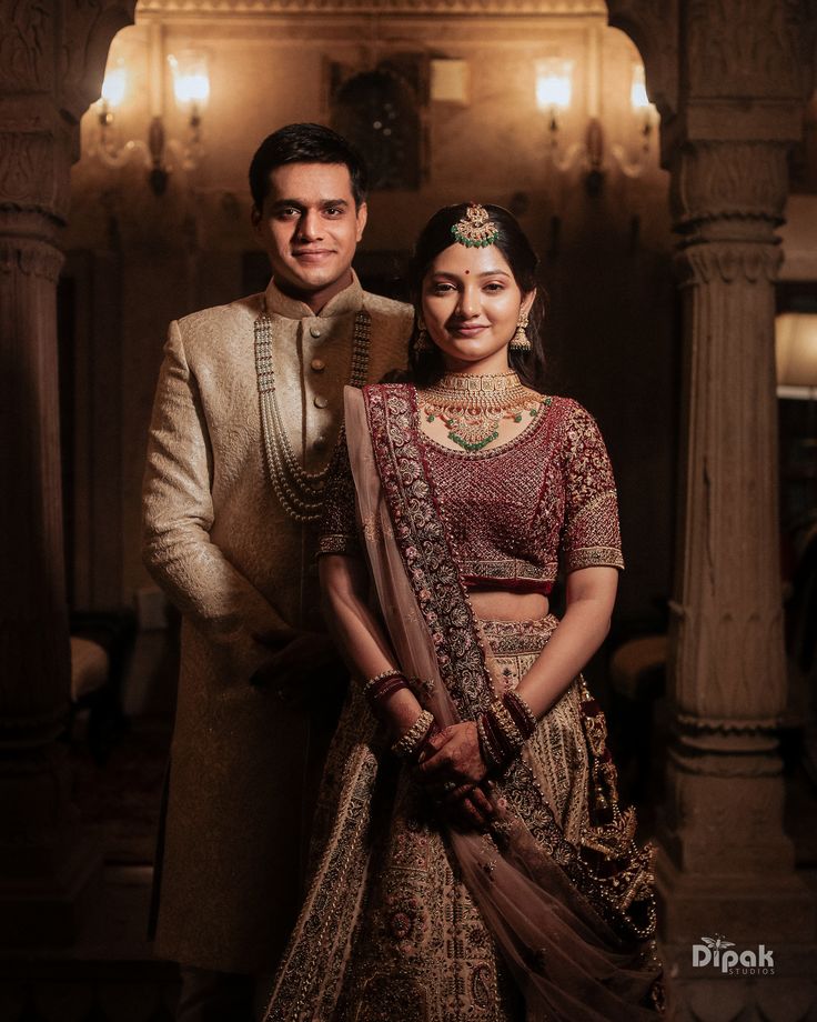 a man and woman standing next to each other in front of some pillars with lights on them