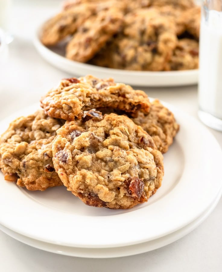 three cookies on a plate next to a glass of milk