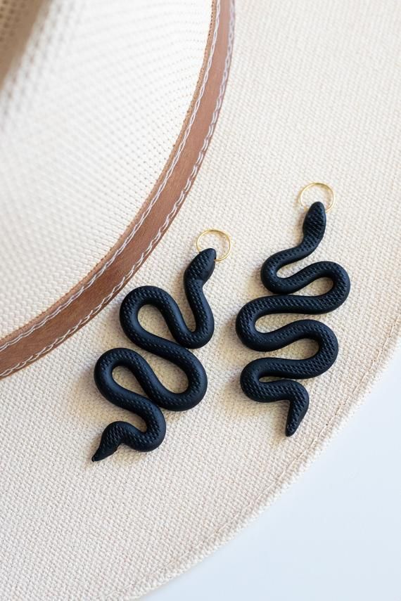 two black snakes are hanging from the side of a hat