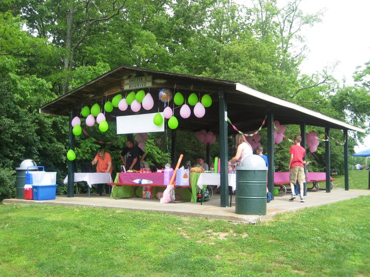 people standing in front of a covered area with balloons and streamers hanging from the roof