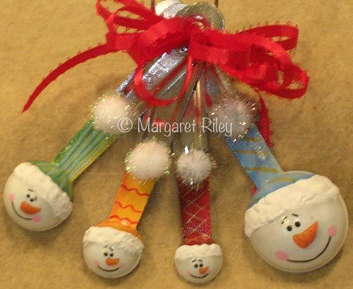 three snowman spoons are hanging from a christmas ornament